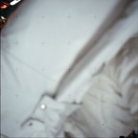 An accidental exposure showing the Reseau plate crosses against a blurry space suit. Photo by NASA.